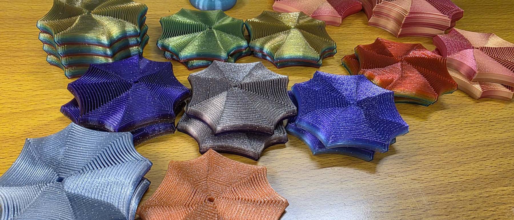 Finished Focus Spirals stacked in gold, green, coral, purple, blue and copper on the studio bench